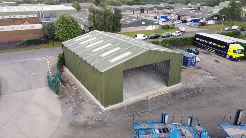 Small green prefabricated steel vehicle storage building supplied and installed in Aldridge by Saredon Steel Buildings Ltd