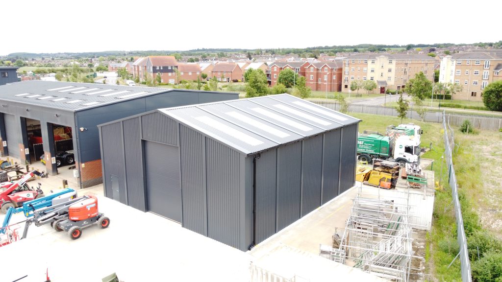 Small grey cladding steel building with rooflights and roller shutter door used for a Paint Shop Building in Kent manufactured by Saredon Steel Buildings Ltd